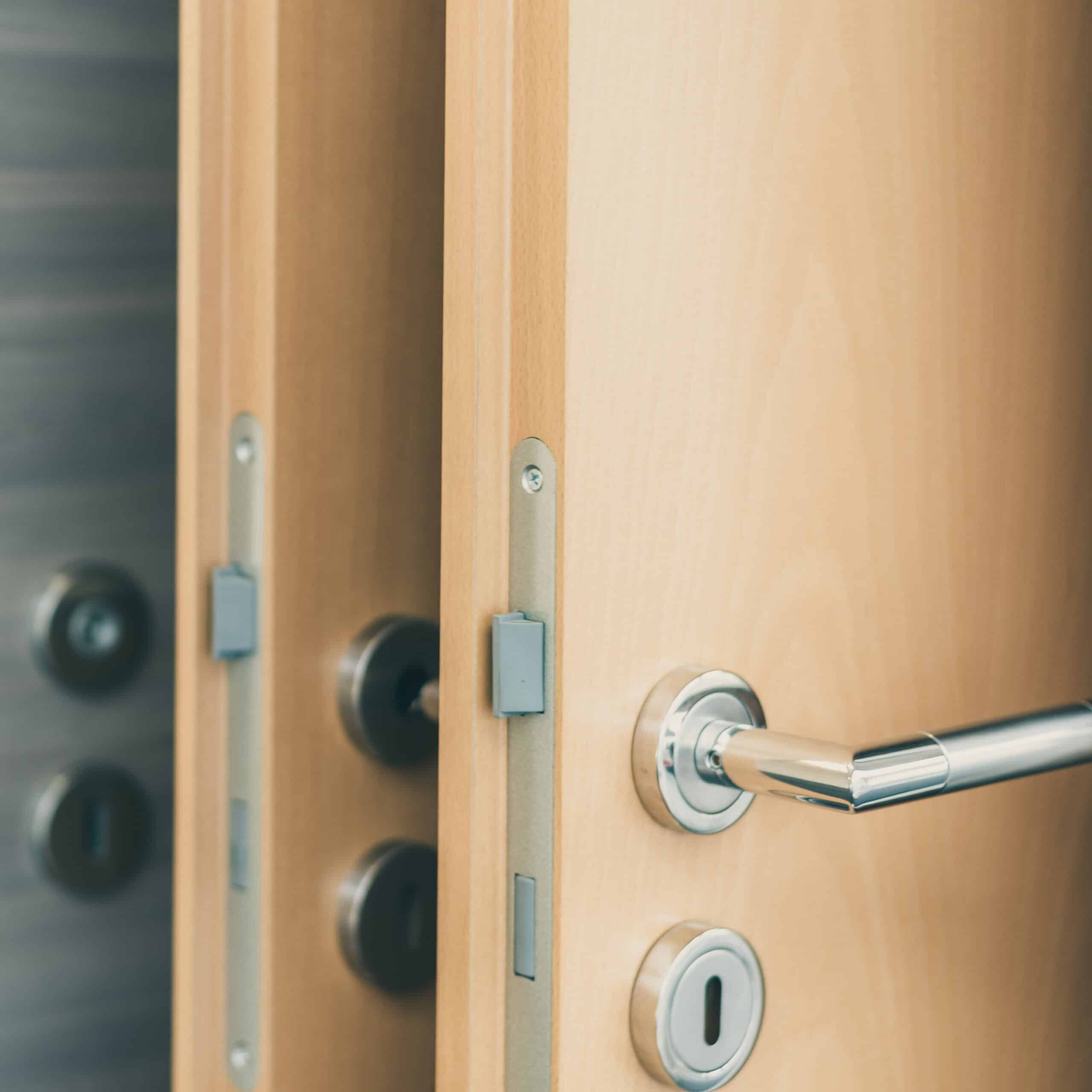 Portes en bois ouvertes avec poignées métalliques brillantes et serrures. Détail sur le mécanisme et les verrous.